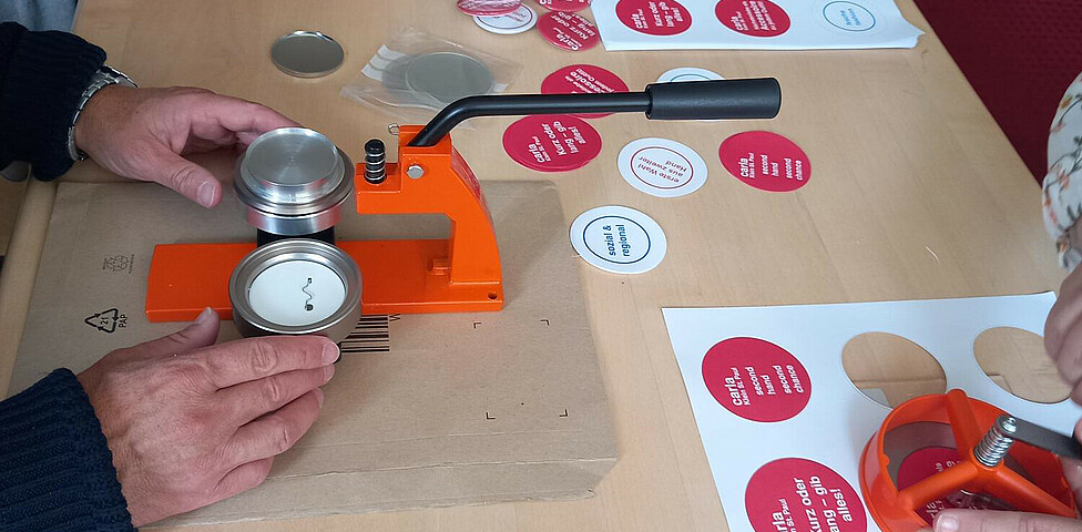 Menschen unseres Projektes stanzen Button-Sprüche aus um sie dann mit einer Button-Maschine zusammenzusetzen.
