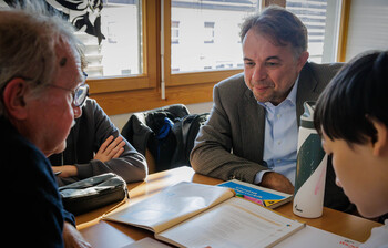 Erwachsener im Gespräch mit Schülern bei der Lernbetreuung im Lerncafè in Kärnten.