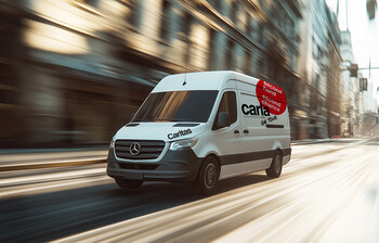 Ein weißer Kastenwagen mit der Aufschrift carla on tour fährt über eine Straße.
