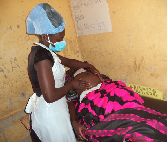 Eine Pflegerin untersucht den Bauch einer Schwangeren.