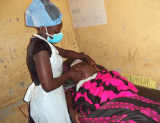 Eine Pflegerin untersucht den Bauch einer Schwangeren.