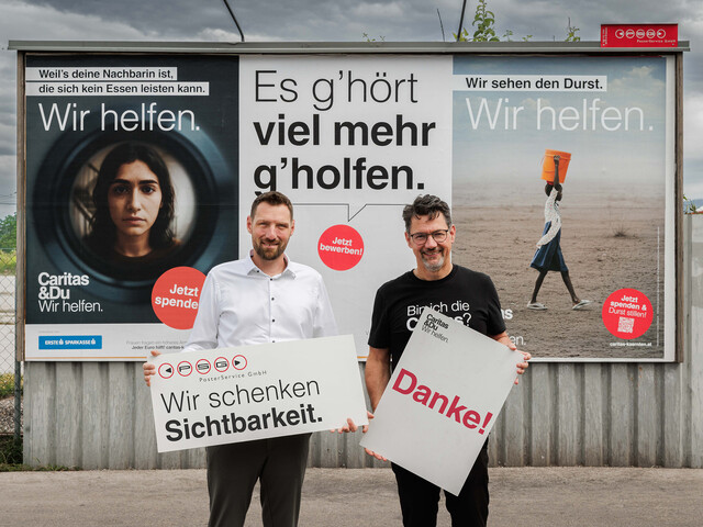 David Edlinger, Geschäftsführer PSG Poster Service GmbH und Caritasdirektor Ernst Sandriesser vor Caritas-Plakaten halten Schilder mit „Wir schenken Sichtbarkeit“ und „Danke!“.