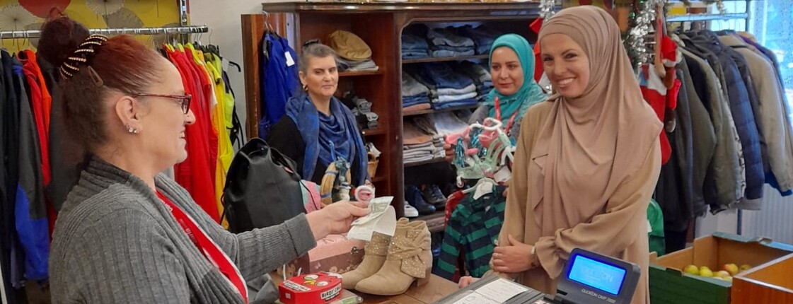 An der Kasse im Carla-Laden verkauft eine Frau einer Kundin Ware, im Hintergrund stehen zwei weitere Kundinnen