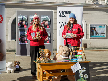 Zwei Frauen präsentieren Infomaterial vor Bäreninstallation zur Frühförderung am Neuen Platz.