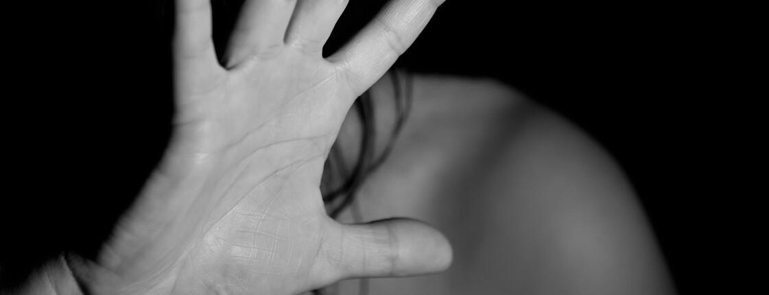 Ein schwarz-weißes Bild auf der eine Frau zu sehen ist, die ihre eigene Hand vor ihr Gesicht hält.