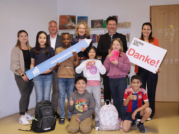 Gruppe von Kindern und Erwachsenen im Lerncafé Don Bosco Klagenfurt hält Spendenzeichen von Wietersdorfer und „Danke“.