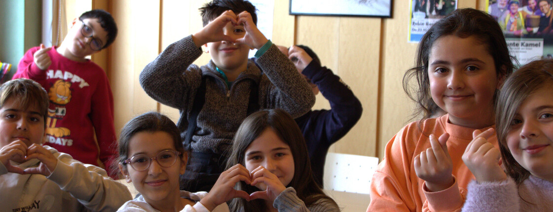 Schüler*innen der Lerncafés in Villach zeigen verschiedene Herz-Gesten mit den Händen.