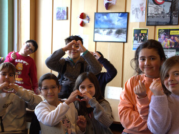 Schüler*innen der Lerncafés in Villach zeigen verschiedene Herz-Gesten mit den Händen.