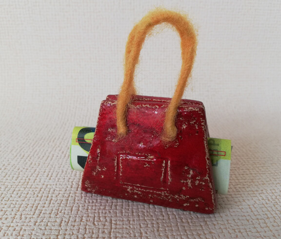 Eine aus Ton gefertigte Tasche mit einem 100-Euro-Gelschein in ihr.