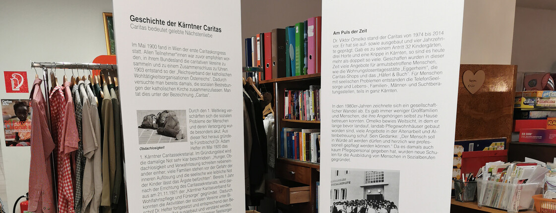 Zwei große weiße Säulen mit den wichtigsten Informationen zu 100 Jahre Caritas stehen im Second-Hand-Markt carla.