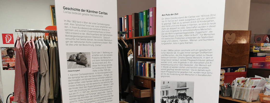 Zwei große weiße Säulen mit den wichtigsten Informationen zu 100 Jahre Caritas stehen im Second-Hand-Markt carla.