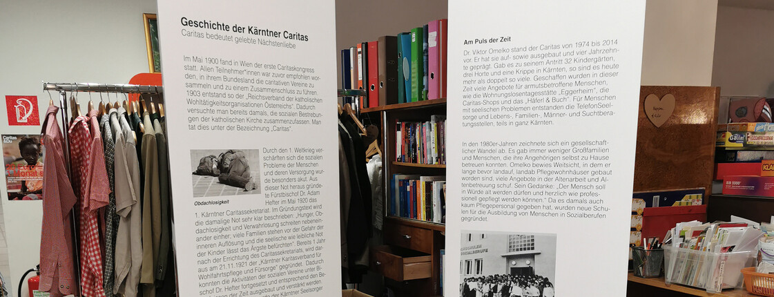 Zwei große weiße Säulen mit den wichtigsten Informationen zu 100 Jahre Caritas stehen im Second-Hand-Markt carla.