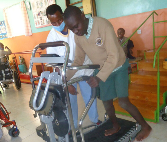 Ein junger afrikanischer Mann geht auf einem Laufband. Ein Mediziner überwacht die Übung.