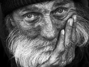 Porträt eines nachdenklichen älteren Mannes  Älterer Mann mit Bart und Mütze blickt ernst in die Kamera, stützt das Gesicht auf seine Hand