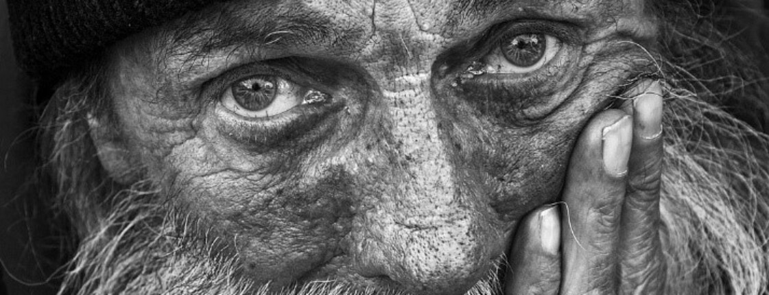 Älterer Mann mit Bart und Mütze blickt ernst in die Kamera, stützt das Gesicht auf seine Hand