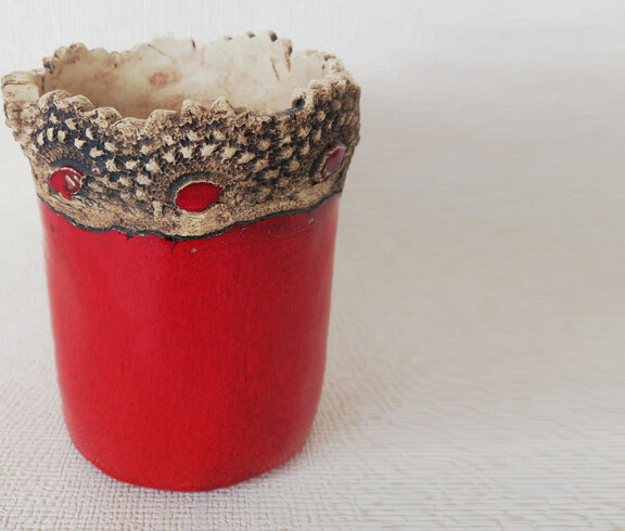 Ein Blumentop in rot mit einem kunstvollverzierten oberen Rand.