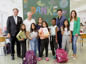 Caritasdirektor Mag. Ernst Sandriesser (re) und Magistra Roberta Striedinger von der Caritas danken Mag. Siegfried Huber (li) für die langfristige Unterstützung der Lerncafés. Auf dem Foto sind auch Lerncafé-Kinder und ein engagierter Lernhelfer zu sehen.