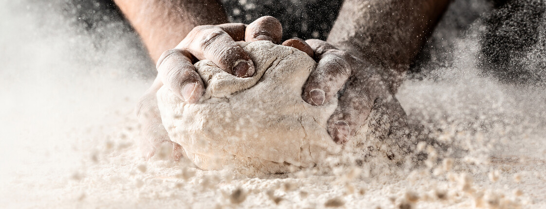 Clap hands of baker with flour. Beautiful and strong men's hands knead the dough make bread, pasta or pizza. Powdery flour flying into air