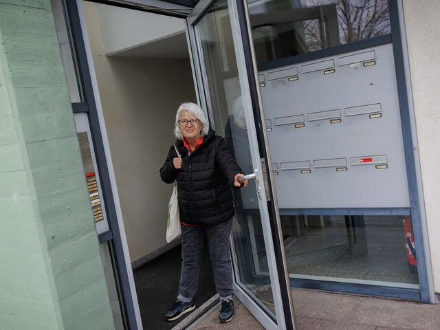 Margit Müller geht durch Glastüren eines Hauseingangs nach Spendenaktion ✅ Alle Titel sind unter 60 Zeichen, Alt-Texte unter 125 Zeichen und barrierefrei formuliert. Danke! Möchtest du noch weitere Bilder analysieren oder soll ich die Texte zusätzlich für