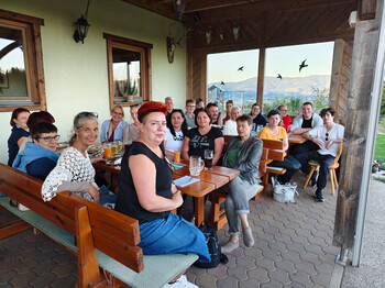 Mitarbeitende der PMS Group und Pflegekräfte vom Haus Elisabeth sitzen bei Getränken auf einer Terrasse mit Blick ins Tal.