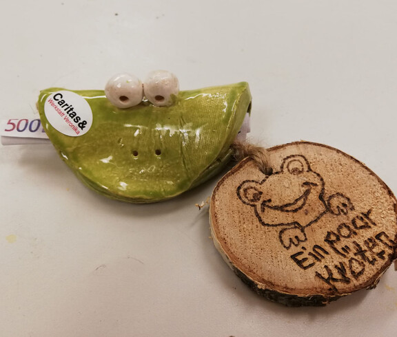 Ein Froschgesicht aus Ton, in dem ein Geldschein steckt mit einem Holzanhänger mit der Aufschrift "Ein paar Kröten"