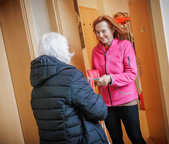 Margit Müller spricht mit einer Person an einer Haustür während der Haussammlung
