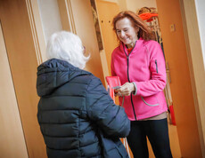 Margit Müller spricht mit einer Person an einer Haustür während der Haussammlung