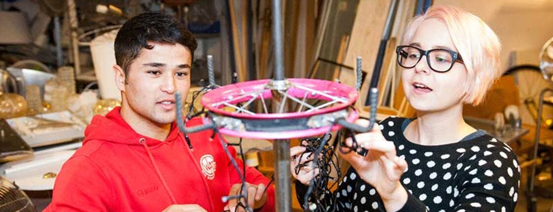 Ein junger Mann und eine Frau basteln mit einer Lichterkette. 