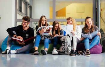 Ein Schüler und fünf Schüler*innen sitzen auf Sitzsäcken im Gand der Schule und lernen miteinander.