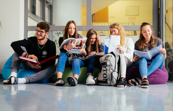 Ein Schüler und fünf Schüler*innen sitzen auf Sitzsäcken im Gand der Schule und lernen miteinander.