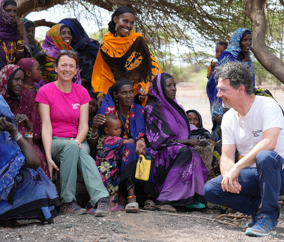 Caritas-Mitarbeiter*innen im Austausch mit Frauen einer nomadischen Gemeinschaft in Kenia – zuhören, verstehen und gemeinsam Lösungen finden.