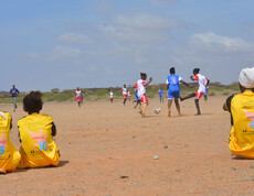 Afrikaner*innen spielen Fußball. 