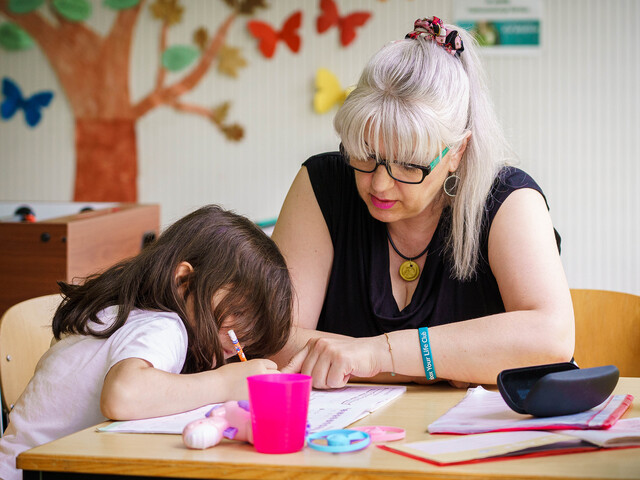 Eine Frau unterstützt ein Mädchen beim Lernen im Lerncafé der Caritas Kärnten – ein Ort für Bildung und Geborgenheit.