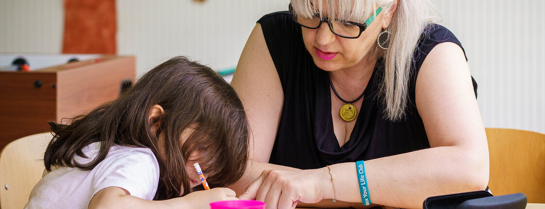 Eine Frau unterstützt ein Mädchen beim Lernen im Lerncafé der Caritas Kärnten – ein Ort für Bildung und Geborgenheit.