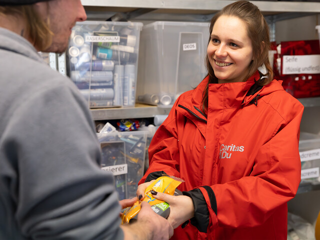 Eine Mitarbeiterin des Eggerheimes gibt einem Besucher der Notschlafstelle Hygieneartikel aus.