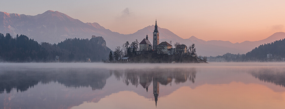 Eine Kirche, die auf einer kleinen Insel mitten in einem See steht mitten im Abendrot.
