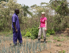 Projektreferentin Theresa Sacher besucht die Zwiebel-Farm eines Projektbegünstigten und steht mit diesem in seinem eigenen Feld.