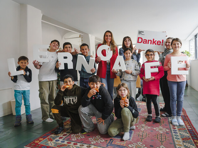 Gruppe von Kindern und zwei Erwachsenen im Lerncafé, hält Buchstaben „LERNCAFE“ und ein „Danke!“-Schild