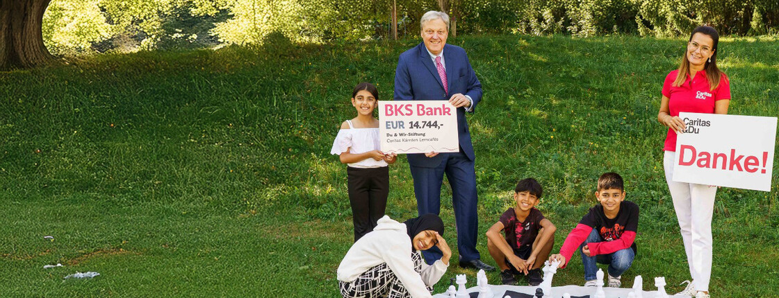 Kinder mit großem Schachspiel, Spendenscheck über 14.744 € für Caritas-Lerncafés übergeben.