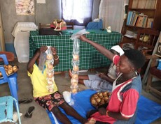 Drei Frauen sitzen am Boden und packen selbstgemachte Muffins in Plastiktüten für den Verkauf.
