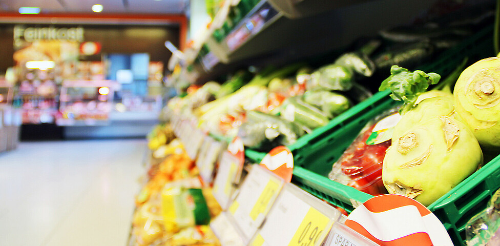 Ein Gemüseregal im SPAR Supermarkt Perspektive Handel in Villach, im Hintergrund sieht man die Frischfleisch-Theke.