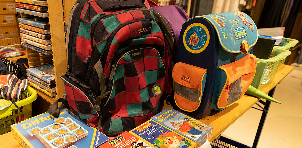 Zwei Schultaschen stehen auf einem Tisch, daneben liegen Kinderspiele.