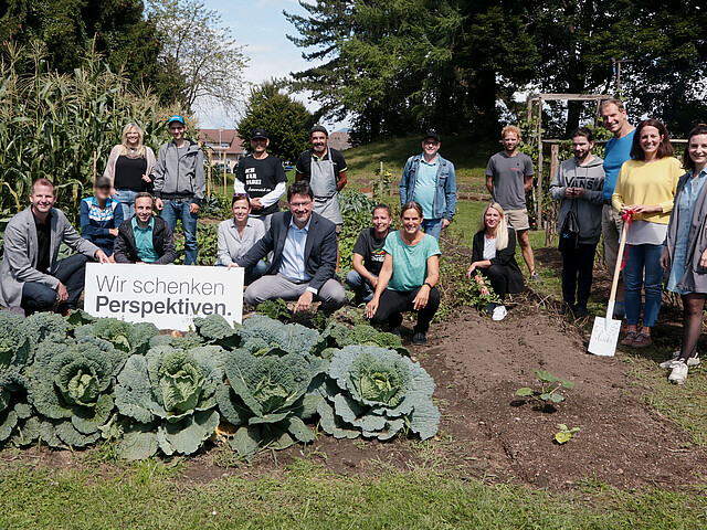 Die Flex Foundation mit den Projektverantwortlichen sowie Menschen, die im Beschäftigungsprojekt Arbeit gefunden haben, vor den Beeten unseres grown.care-Gartens. Unser Beschäftigungsprojekt grown.care ein Garten indem allerlei Gemüse angebaut wird, wird von Unternehmen finanziert.