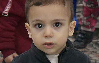 Ein kleiner Junge aus Syrien sieht mit großen Augen in die Kamera.