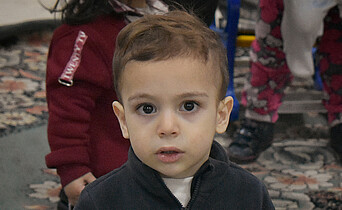 Ein kleiner Junge aus Syrien sieht mit großen Augen in die Kamera.