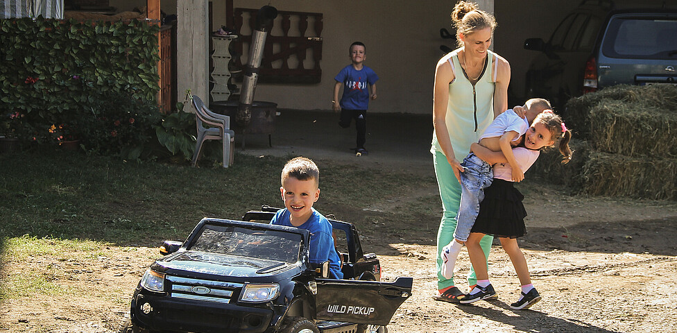 Doni ein Junge mit Behinderungen spielt mit seiner Mutter seinem Bruder und seiner Schwester im Hof.