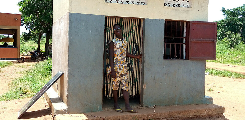 Ein junger Mann steht im Eingang seines eigenen kleinen Barber-Shops in Uganda.
