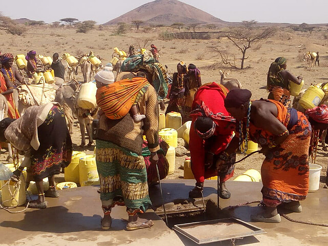 Afrikaner*innen holen gemeinschaftlich Wasser aus den Tiefen Brunnen, während im Land eine Dürre herrscht.