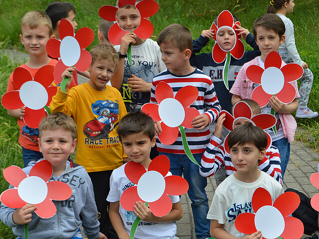 Eine Kindergruppe mit roten Blumen in der Hand aus dem Frühförderungszentrum im Kosovo.