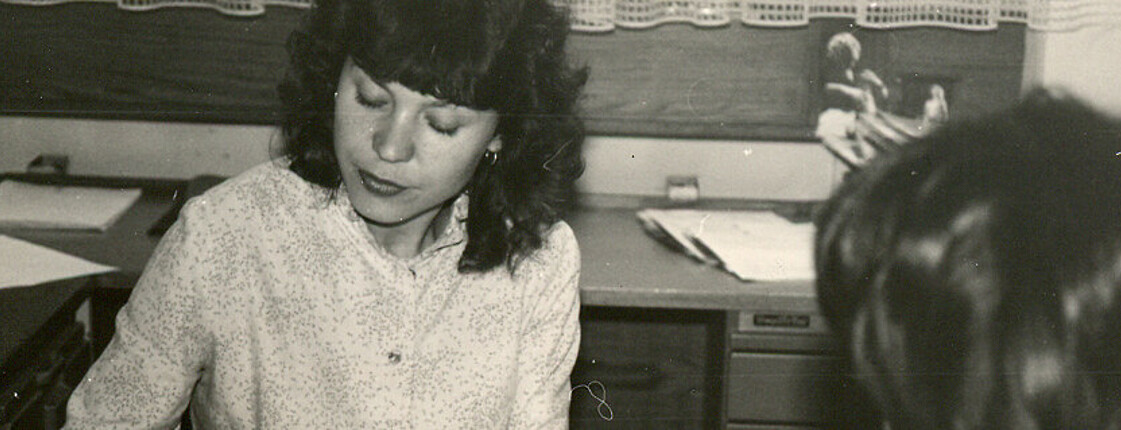 Ein schwarz-weiß Foto von einer Dame die eine Frau in der Sozialberatung berät.